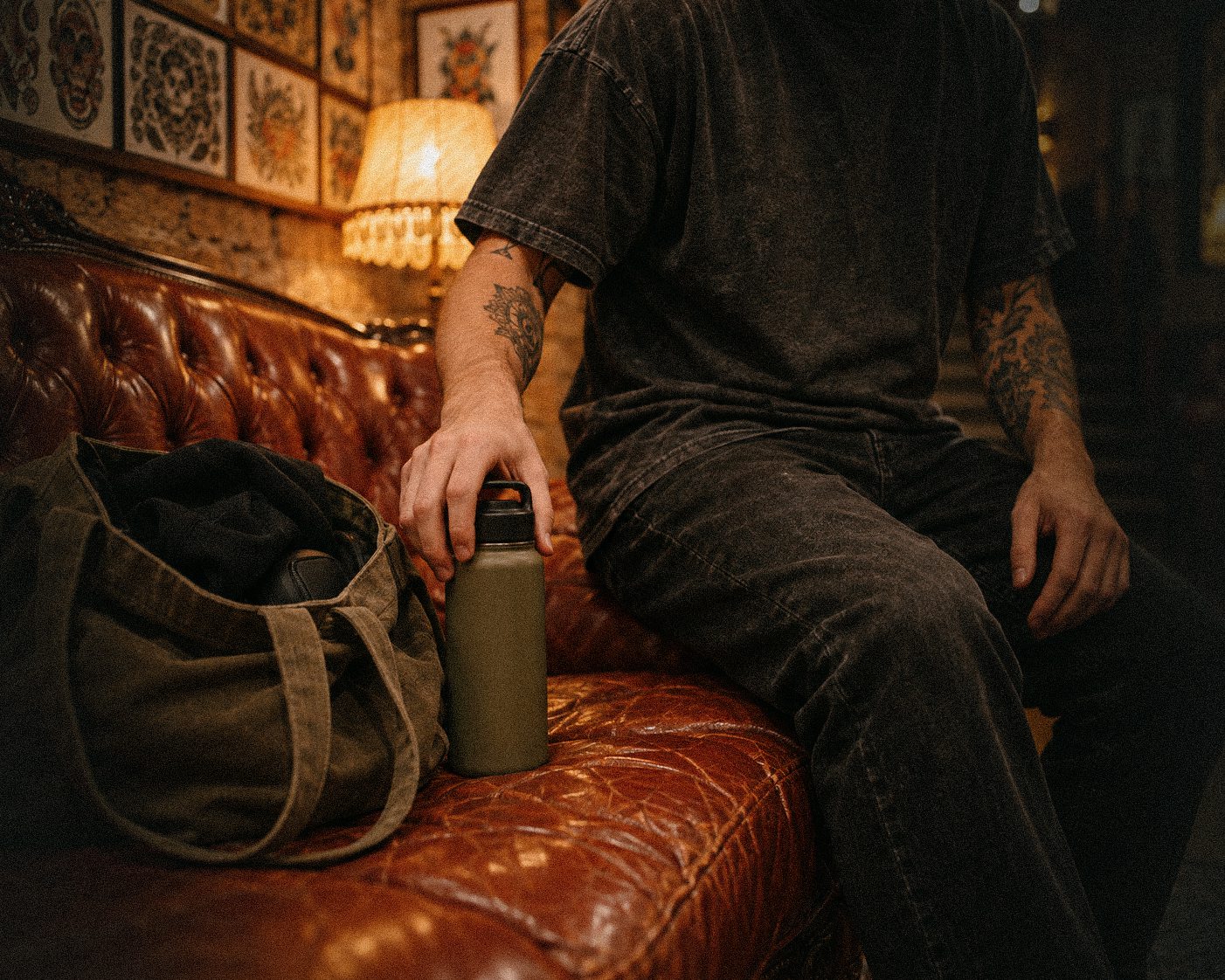 A client with a water bottle and a bag sits on a leather sofa before a session