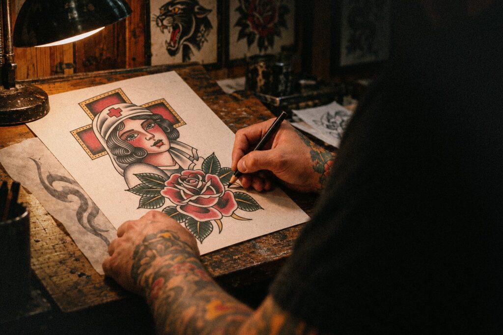A tattoo artist draws a traditional design of a woman with a rose